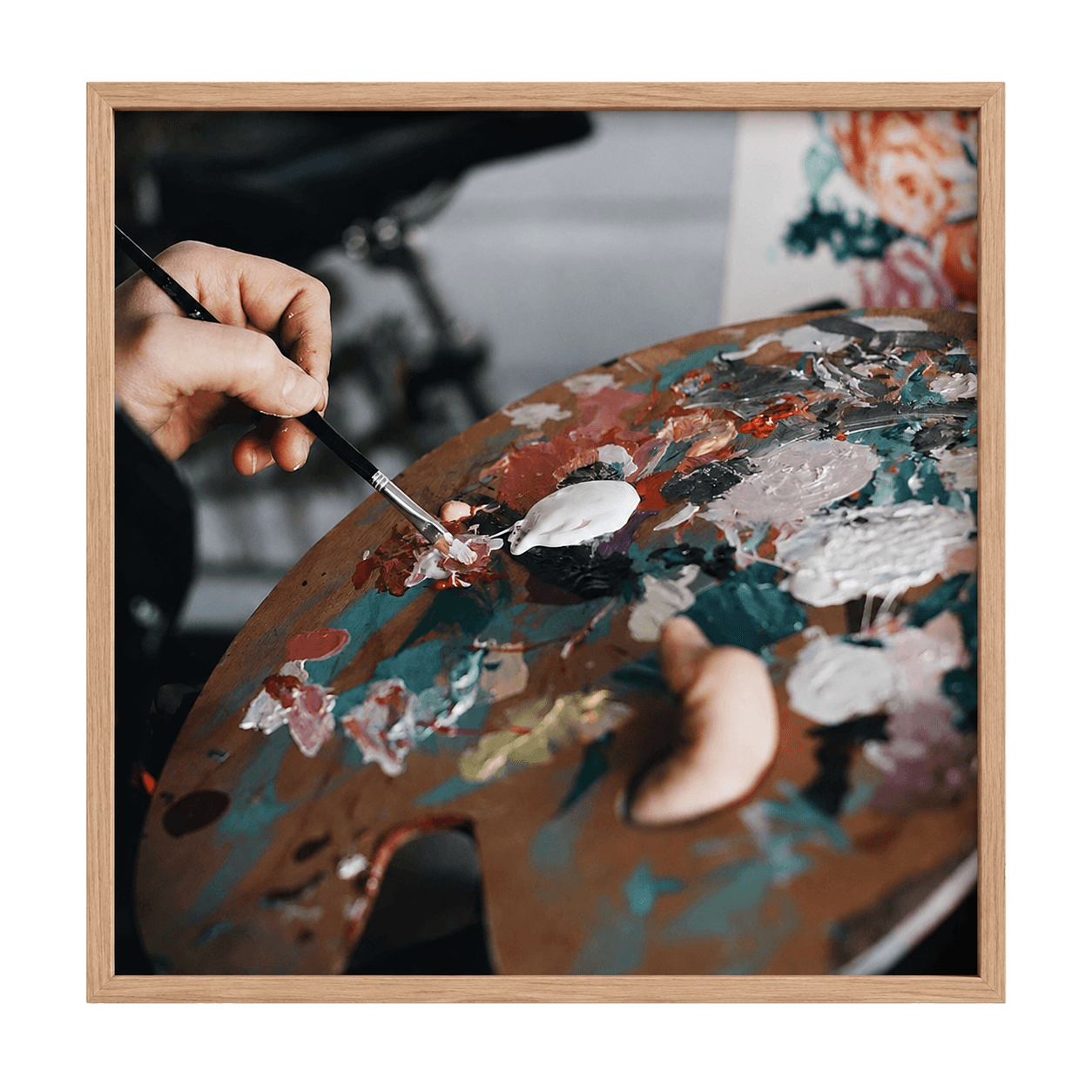 Connie's hands mixing paint on a palette in the studio