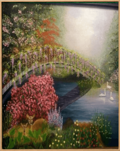 Painted garden bridge over a still pond, banked with pink blossom